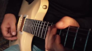 Stüdyoda beyaz gitar çalan müzisyen.