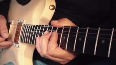 Stüdyoda beyaz gitar çalan müzisyen.