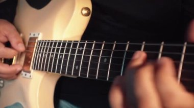 Stüdyoda beyaz gitar çalan müzisyen.
