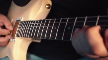 Stüdyoda beyaz gitar çalan müzisyen.