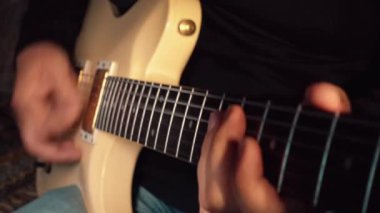 Stüdyoda beyaz gitar çalan müzisyen.