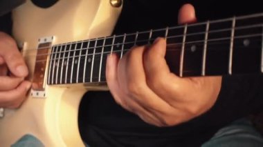 Stüdyoda beyaz gitar çalan müzisyen.