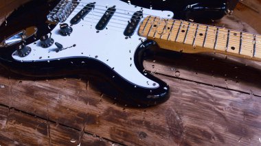Su damlalarıyla birlikte cam arkasındaki tahtanın üzerinde elektro gitar var.