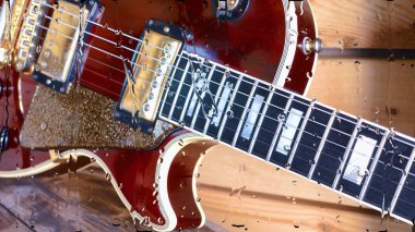 Su damlalarıyla birlikte cam arkasındaki tahtanın üzerinde elektro gitar var.