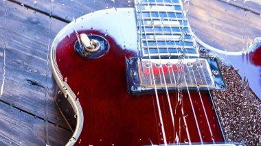 Su damlalarıyla birlikte cam arkasındaki tahtanın üzerinde elektro gitar var.