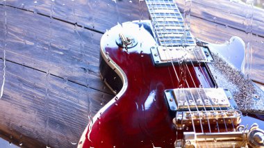 Su damlalarıyla birlikte cam arkasındaki tahtanın üzerinde elektro gitar var.