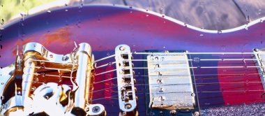 Su damlalarıyla birlikte cam arkasındaki tahtanın üzerinde elektro gitar var.
