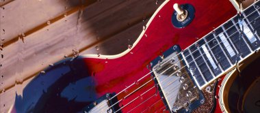 Su damlalarıyla birlikte cam arkasındaki tahtanın üzerinde elektro gitar var.