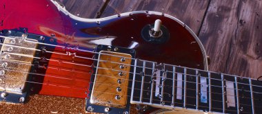 Su damlalarıyla birlikte cam arkasındaki tahtanın üzerinde elektro gitar var.
