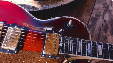 Su damlalarıyla birlikte cam arkasındaki tahtanın üzerinde elektro gitar var.