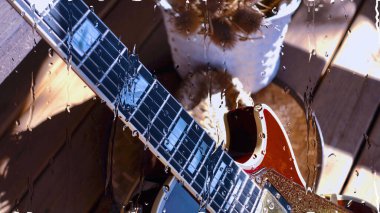 Su damlalarıyla birlikte cam arkasındaki tahtanın üzerinde elektro gitar var.