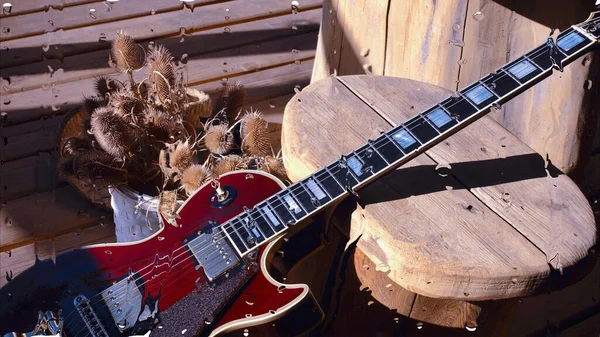 Su damlalarıyla birlikte cam arkasındaki tahtanın üzerinde elektro gitar var.