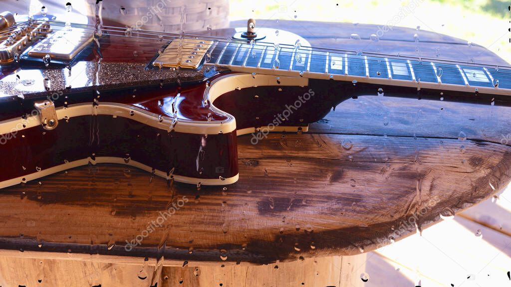 electric guitar on the wooden board behind the glass with water drops