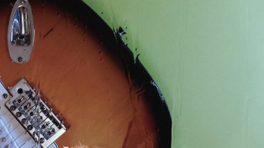Camın arkasında su damlaları olan bir gitar. Renkli arka plan. Boşluğu kopyala