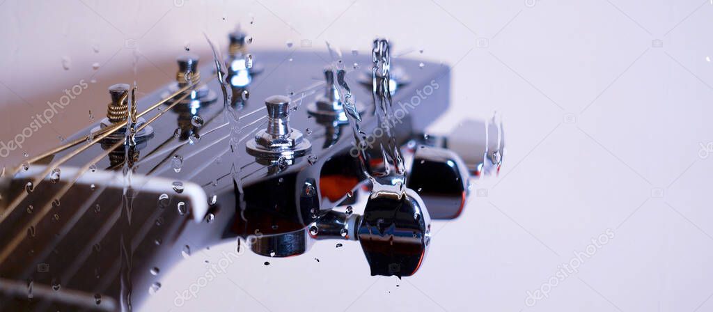 Guitar headstock behind the glass with water drops . Color background . Copy space