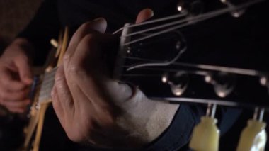 Mikrofonun yanındaki stüdyoda gitar çalan müzisyen.