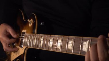 Mikrofonun yanındaki stüdyoda gitar çalan müzisyen.