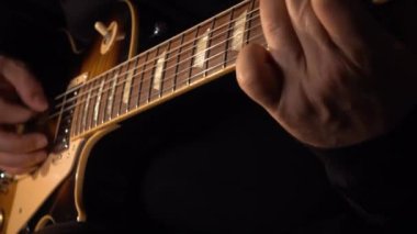 Mikrofonun yanındaki stüdyoda gitar çalan müzisyen.