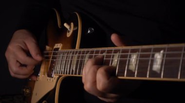 Mikrofonun yanındaki stüdyoda gitar çalan müzisyen.