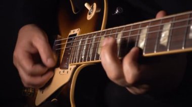 Mikrofonun yanındaki stüdyoda gitar çalan müzisyen.