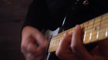 Mikrofonun yanındaki stüdyoda gitar çalan müzisyen.