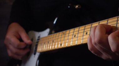 Mikrofonun yanındaki stüdyoda gitar çalan müzisyen.