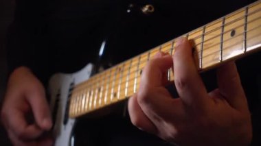 Mikrofonun yanındaki stüdyoda gitar çalan müzisyen.