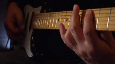 Mikrofonun yanındaki stüdyoda gitar çalan müzisyen.
