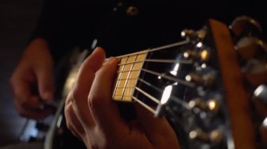 Mikrofonun yanındaki stüdyoda gitar çalan müzisyen.