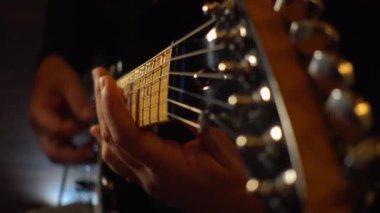 Mikrofonun yanındaki stüdyoda gitar çalan müzisyen.