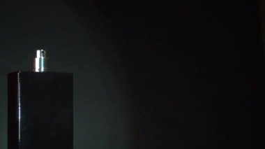 Püskürt. Siyah şişe ve el. koyu arkaplan