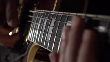 Müzisyen stüdyoda gitar çalar. Yakın plan. Koyu arkaplan