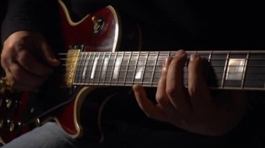 Müzisyen stüdyoda gitar çalar. Yakın plan. Koyu arkaplan