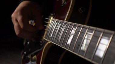 Müzisyen stüdyoda gitar çalar. Yakın plan. Koyu arkaplan