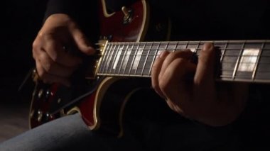 Müzisyen stüdyoda gitar çalar. Yakın plan. Koyu arkaplan