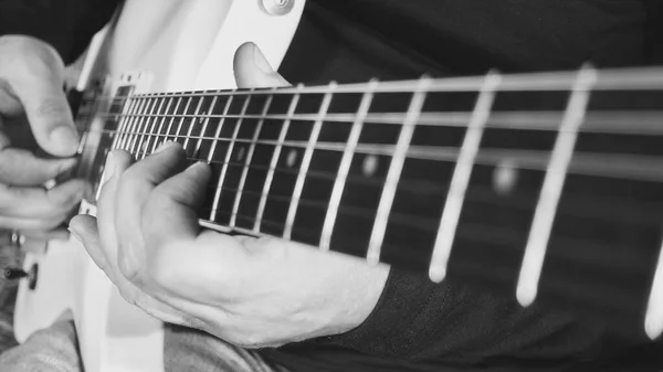 Müzisyen yakın plan gitar çalıyor. Siyah ve beyaz