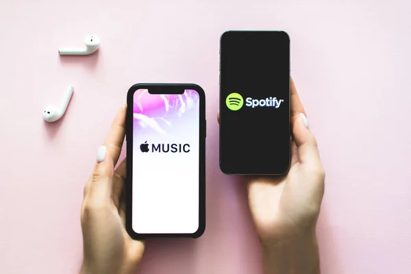 Manos sosteniendo iPhone X con captura de pantalla de la aplicación de música de Apple y Spotify . — Foto de Stock