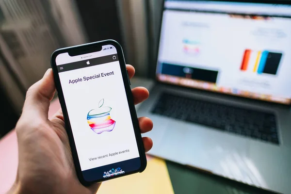Mano sosteniendo el iPhone X con el logotipo del evento especial de Apple 2019 en la pantalla . —  Fotos de Stock