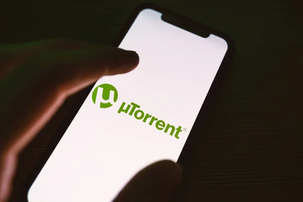 Smartphone de mano con el logotipo de la aplicación Torrent en la pantalla . — Foto de Stock
