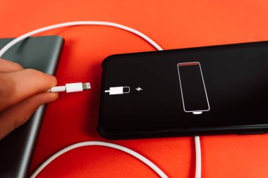 Tam şarjlı bir pil simgesi ile şarj edilen kırmızı arkaplan üzerindeki akıllı telefon.