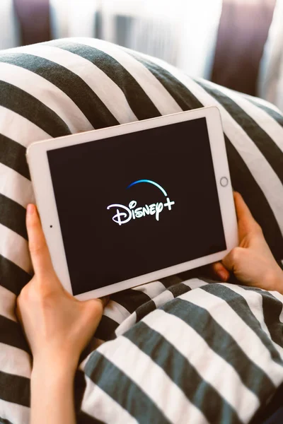 Ekranda Disney artı logosu olan bir tablet tutan kız. — Stok fotoğraf