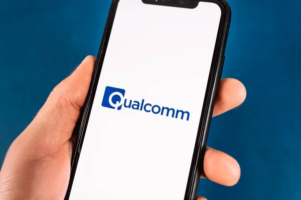 Hand holds smartphone with qualcomm logo. — Stock Photo, Image