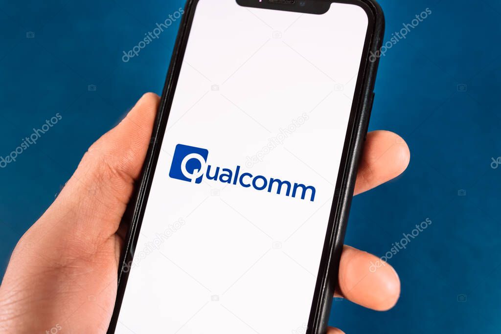 Hand holds smartphone with qualcomm logo. High quality photo.
