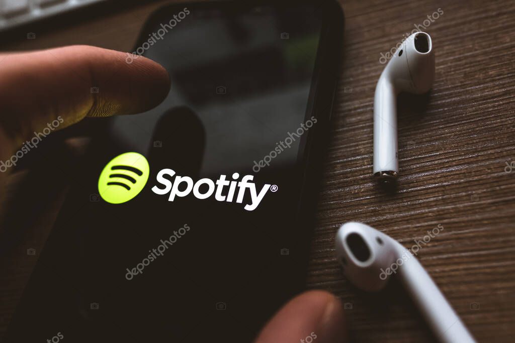 IPhone X and AirPods with screen shot of Spotify app . High quality photo.