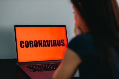 Korkak kadın, koronavirüsün yazıldığı dizüstü bilgisayara bakıyor..