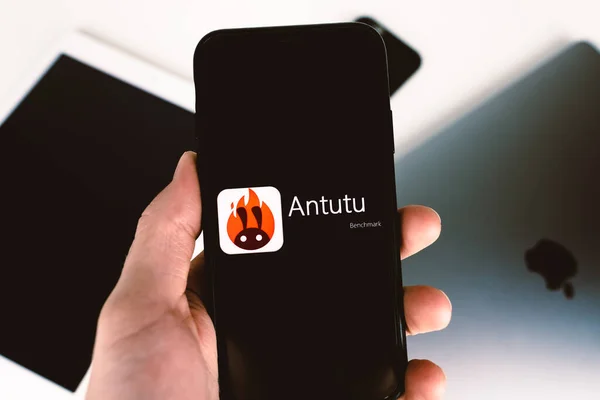 Sostiene el teléfono inteligente con el logotipo de referencia de Antutu en la pantalla — Foto de Stock