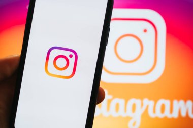 Ekranda instagram uygulaması olan iPhone 'u tutan eller