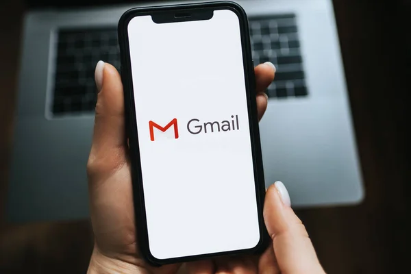 Ręczne trzymanie iPhone z logo aplikacji Gmail na ekranie. — Zdjęcie stockowe