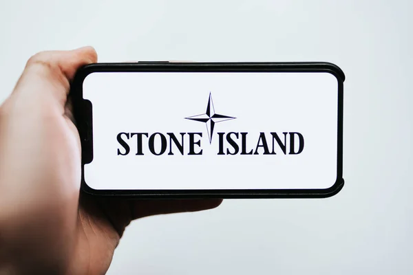 Руки держат iPhone с логотипом Stone Island на экране — стоковое фото