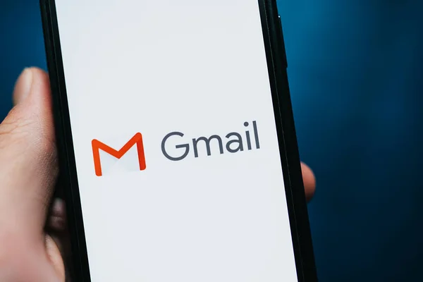 Mão segurando iPhone com o logotipo do aplicativo Gmail na tela . — Fotografia de Stock